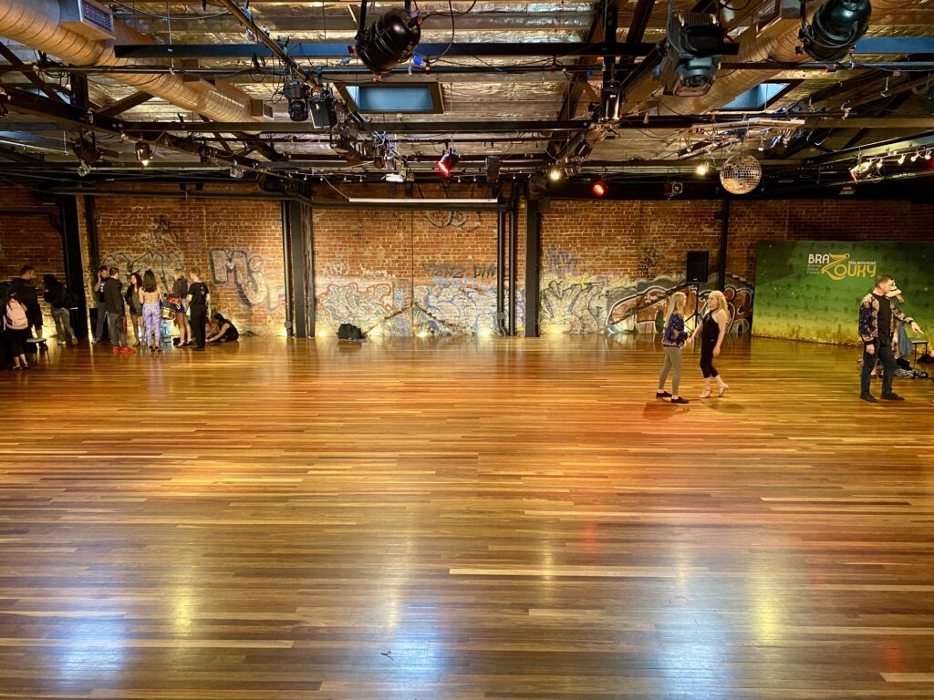 The Space main event hall with hardwood floor, exposed brick walls and stage lighting